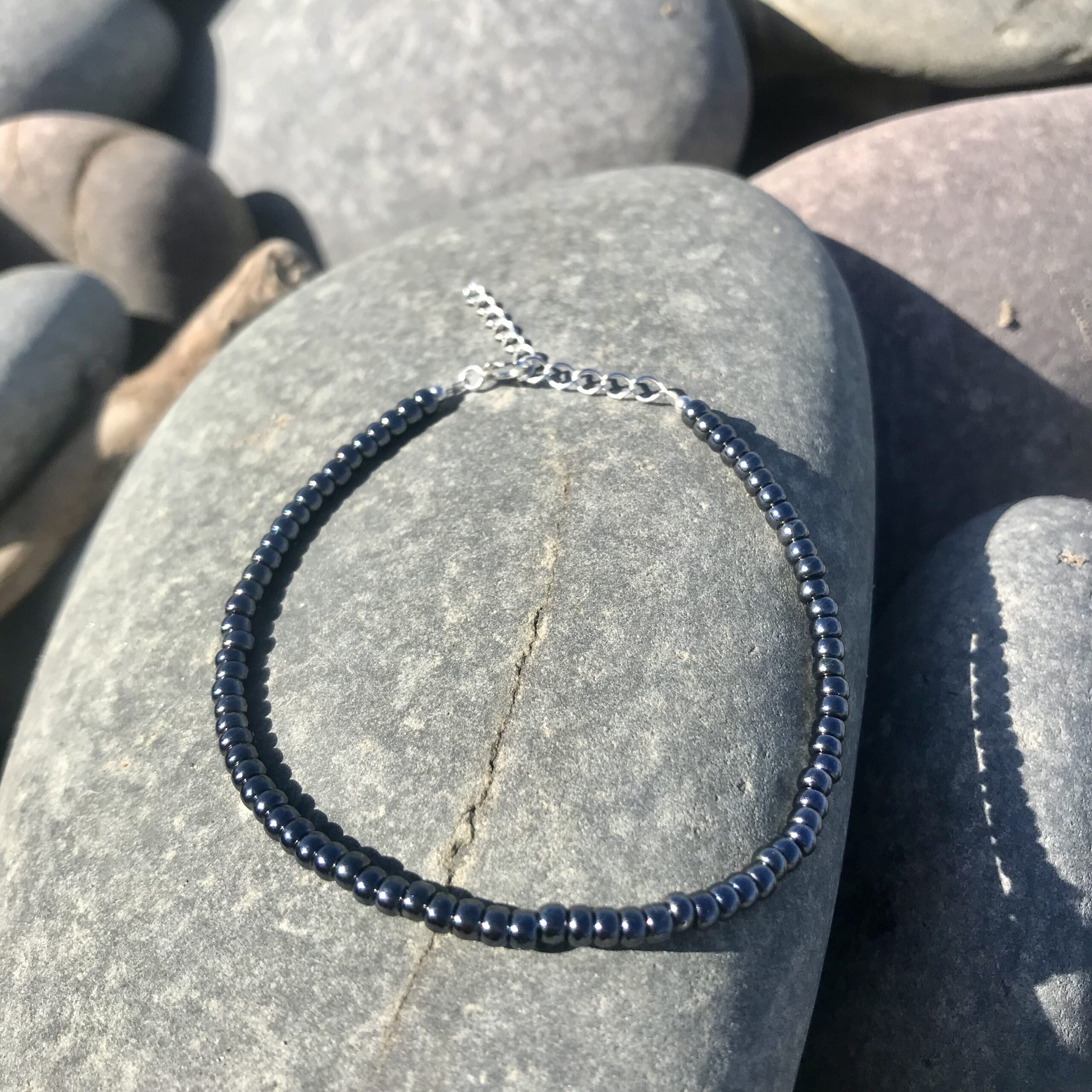 The Charcoal Mist Miyuki Beaded Bracelet, made with a sterling silver clasp and extender chain.