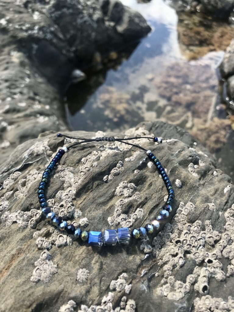 Neptune beaded bracelet by a beach rock pool.