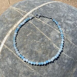 Sterling silver aquamarine bracelet laid out of a large beach pebble.