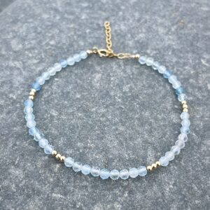 Aquamarine and gold fill beaded bracelet on a beach pebble.