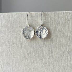 Sterling silver hammered disc earrings catching the light.
